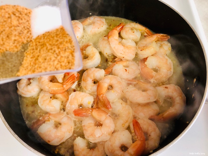 more seasoning being added to the plan of cooking shrimp.